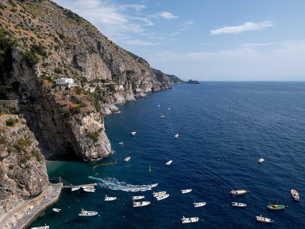 An aerial view of small boats anchored in a cove along the Amalfi Coast near Praiano, Italy