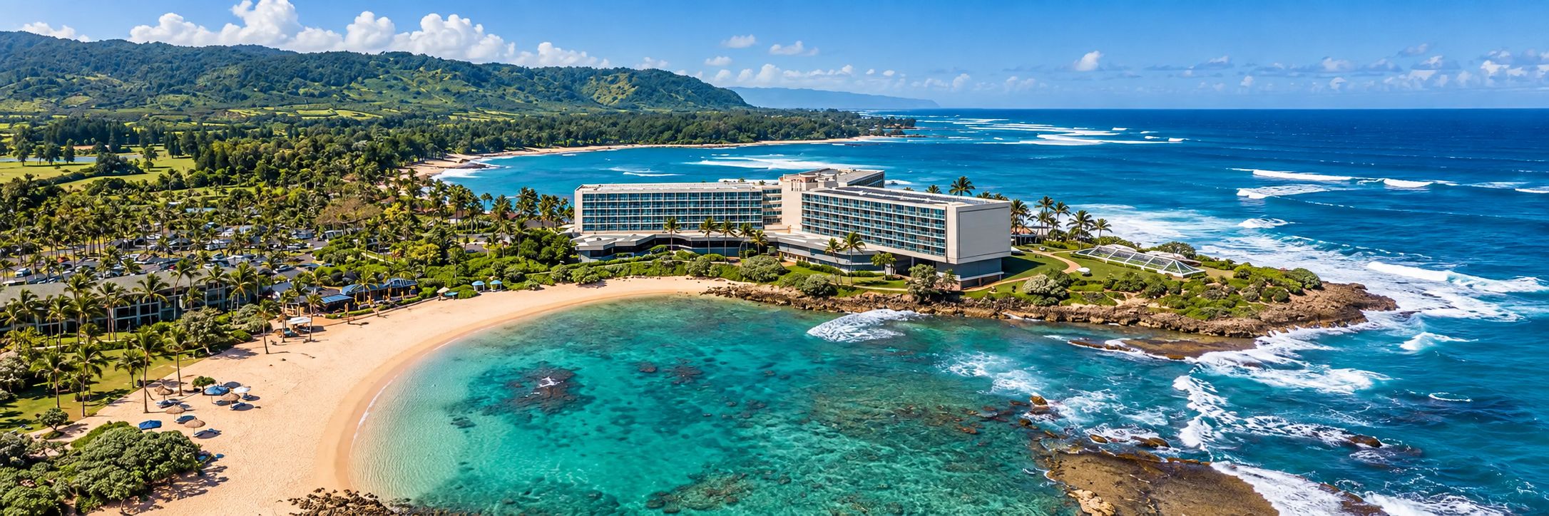 An aerial view of a tropical resort with a turquoise cove and sandy beach along the coastline